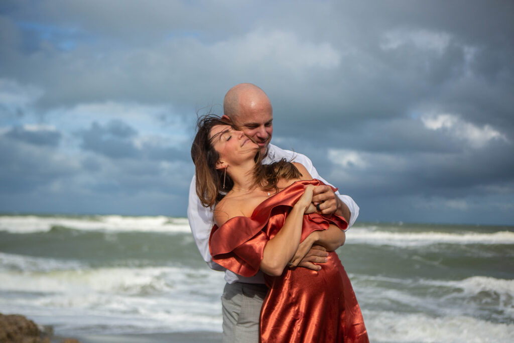 Couple dancing closely with woman’s back against man’s chest as they embrace and sway during romantic engagement session at Blowing Rocks Preserve, Florida.