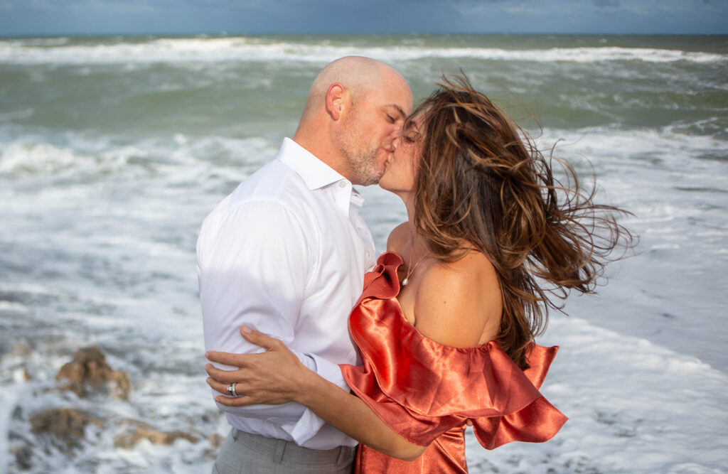 Close-up of couple kissing on the sandy beach during intimate Florida engagement session at Blowing Rocks Preserve.