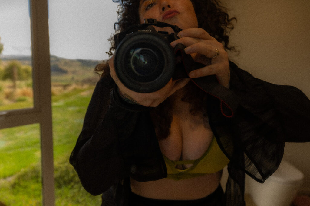 Cecelia takes a mirror selfie with her Canon professional camera while wearing a boudoir outfit, showcasing confidence and artistry in her Te Kuiti, New Zealand destination shoot.