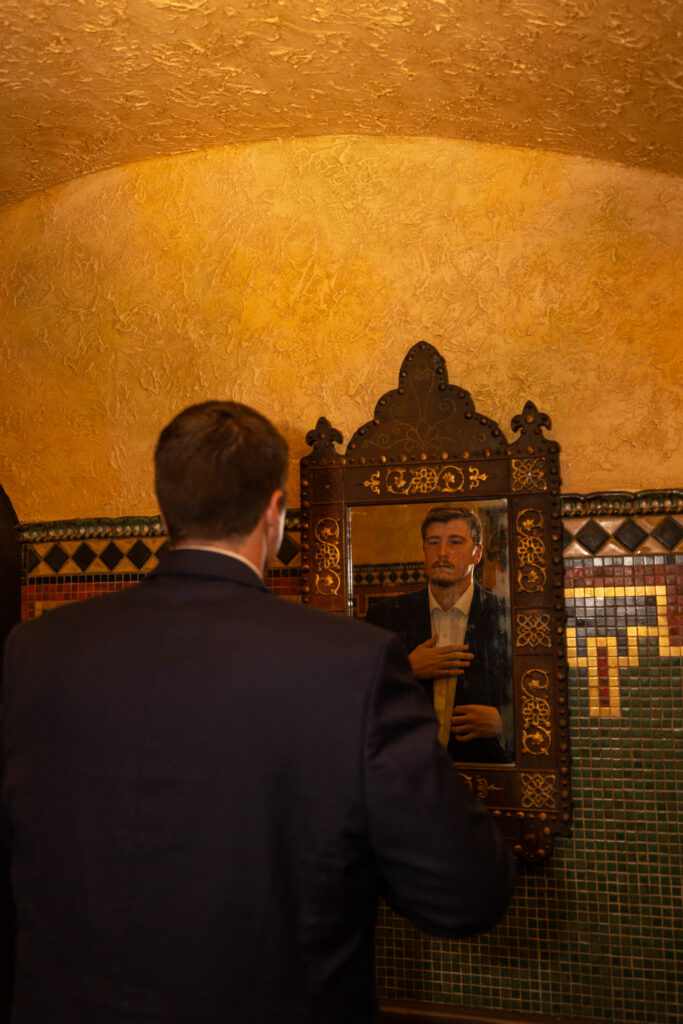 Drake looking at himself in the vintage mirror in the mens bathroom in the Tampa Theatre while CeceTay Productions Captions the engagement session.