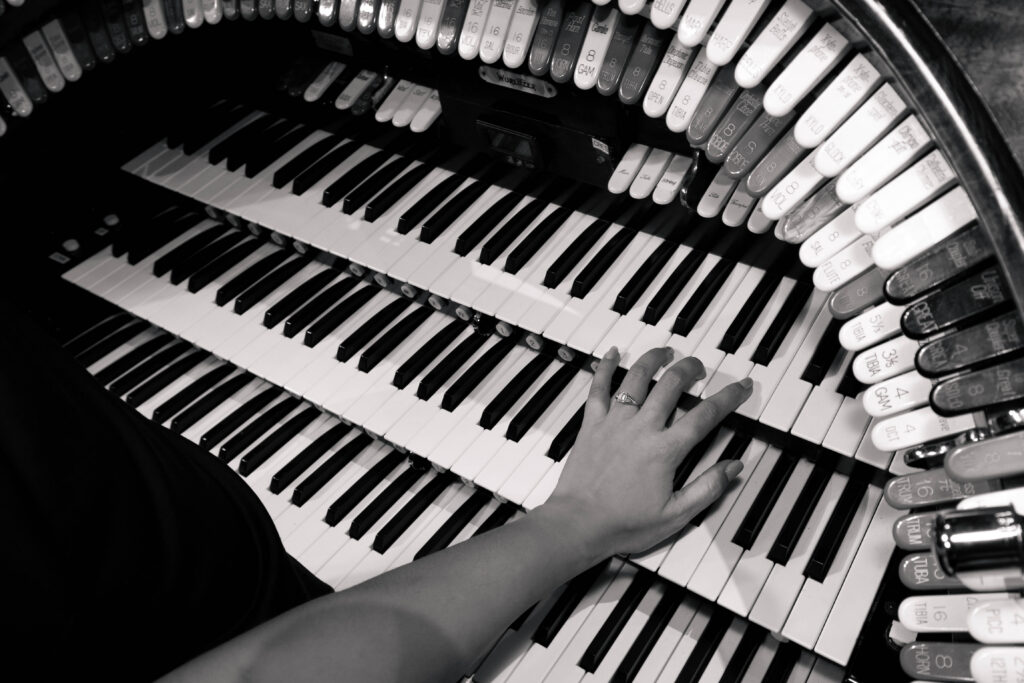 Black and white engagement photography by CeceTay Productions of bride ring on the tampa theatre organ sitting on grooms lap.